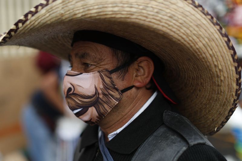 A man wearing a face mask walks amidst outdoor stalls at Mercado Sonora, which reopened ten days ago with measures to reduce congestion and limit the spread of the coronavirus, in Mexico City. (Photo by Rebecca Blackwell/AP Photo)